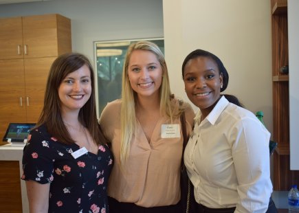three women smile at the camera, all members of the chamber young professionals