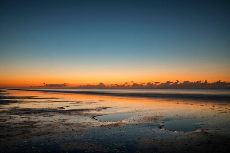 Sunset orange sky against low tide