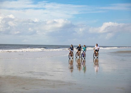 family of four ride bikes along ocean front