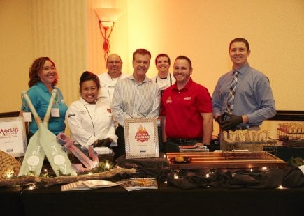 Chef and helpers standing behind their table at event