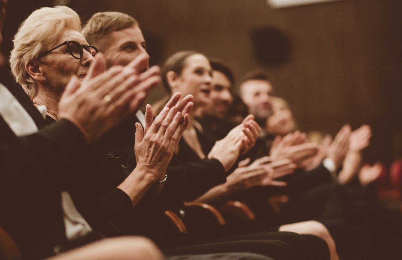 group of people in black tie applaud