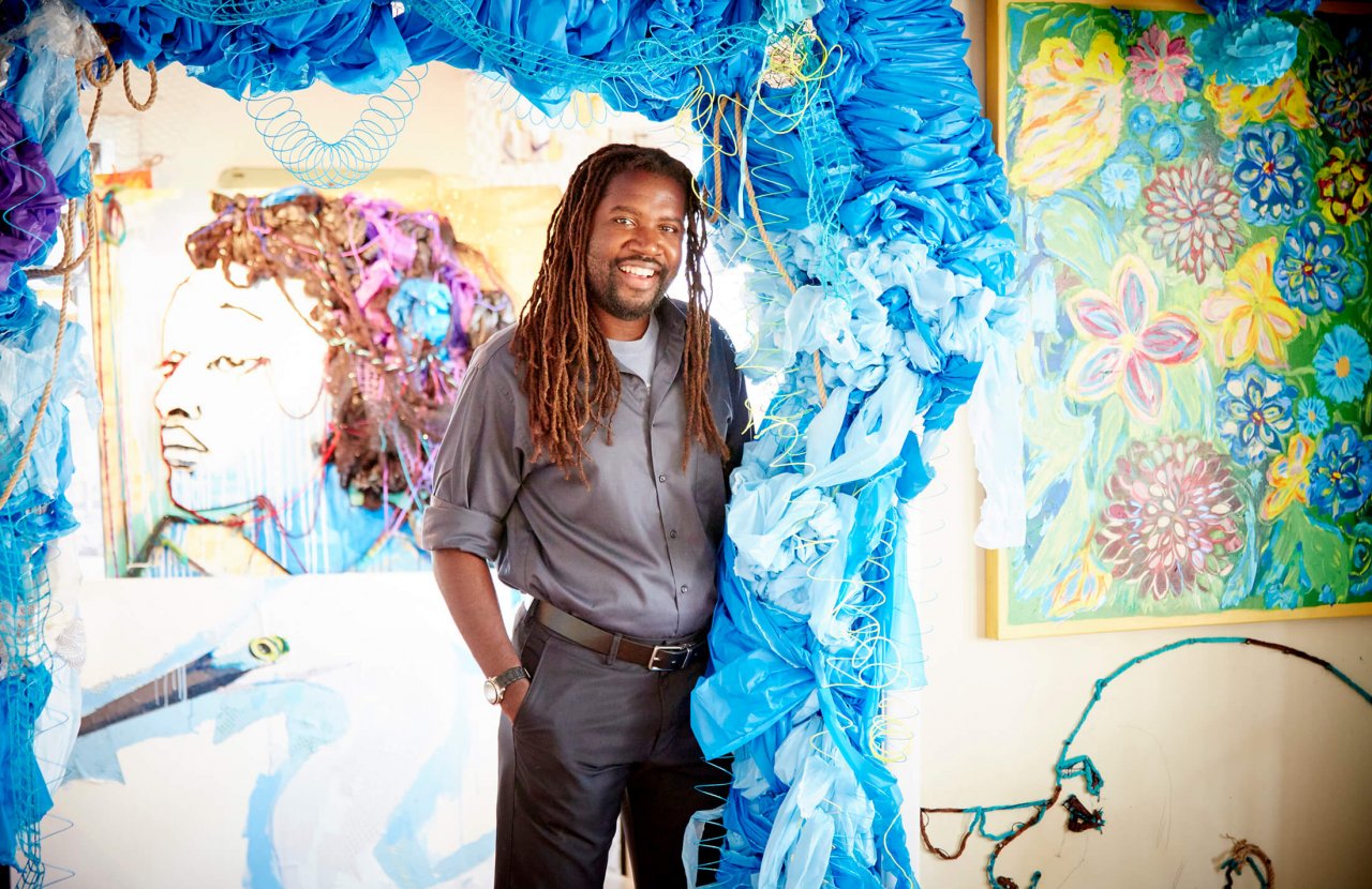 Man stands in front of art installation made of blue yarn