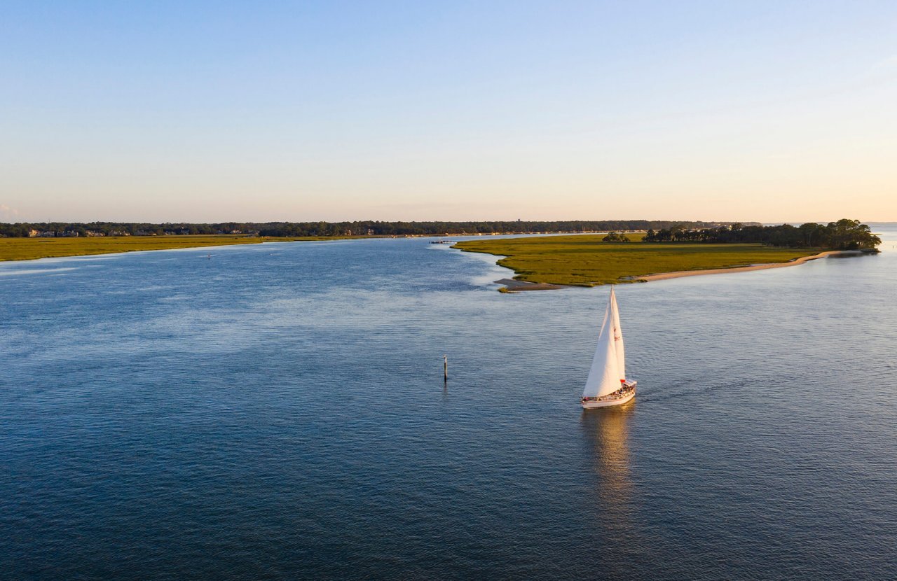 Sailboat with white sails glides along lowlands in Hilton Head Island