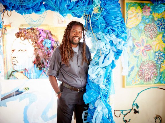 Man stands in front of art installation made of blue yarn