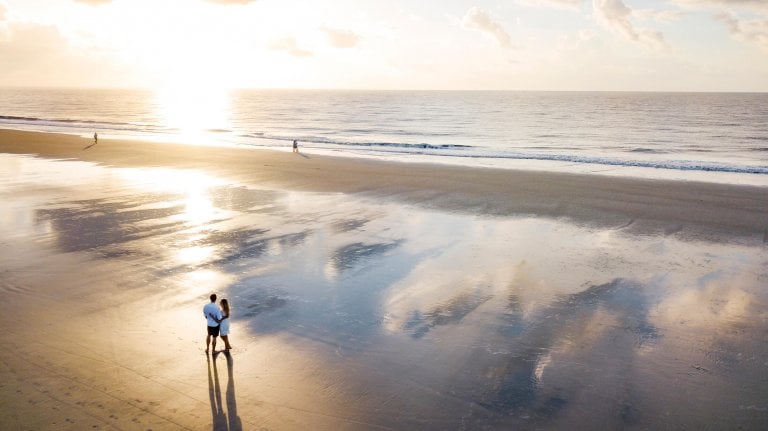 aerial shot of couple hugging on the beach at sun rise