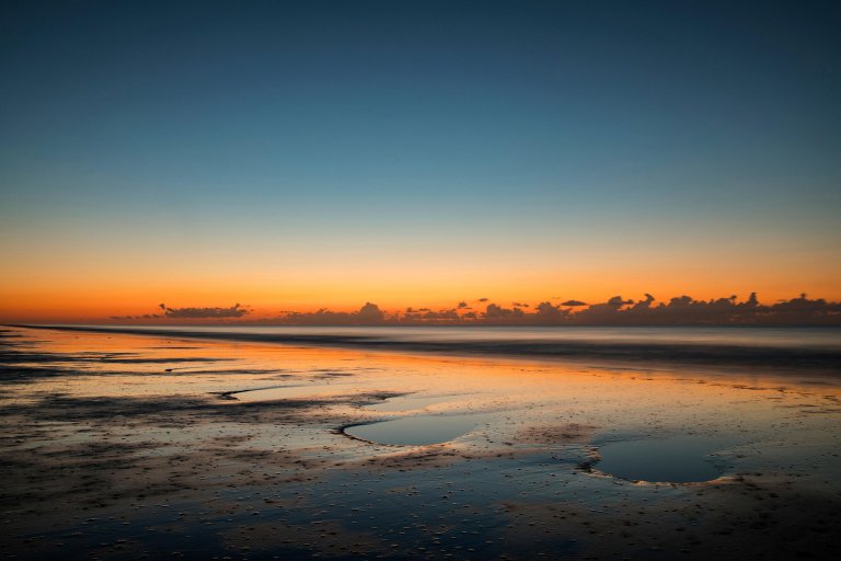 Sunset orange sky against low tide