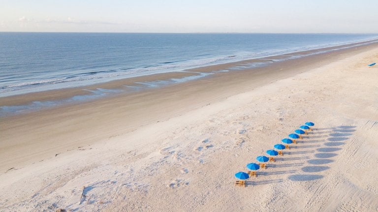 aerial shot of blue umbrella chairs along beach