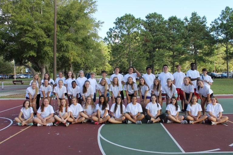 group of youth leaders pose on tennis court in matching outfits