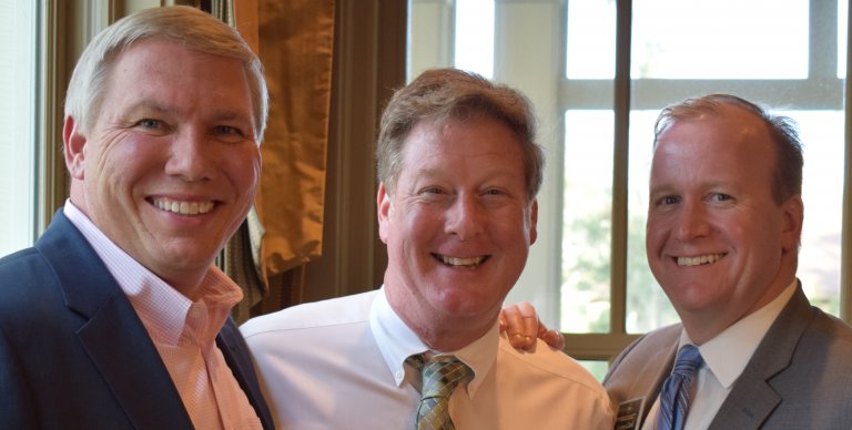 Three well dressed men posing for a picture