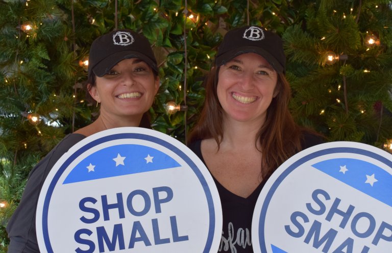 Two women holding shop small signs